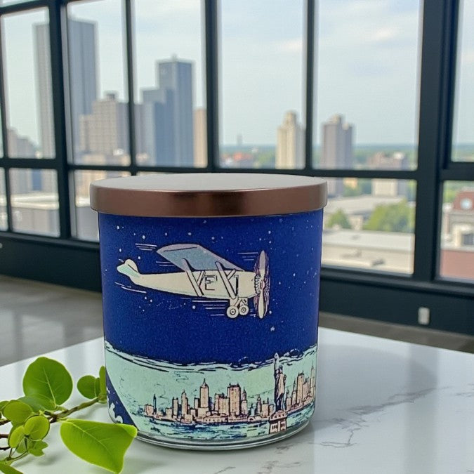 Candle with airplane and cityscape design on a marble surface with a city skyline in the background