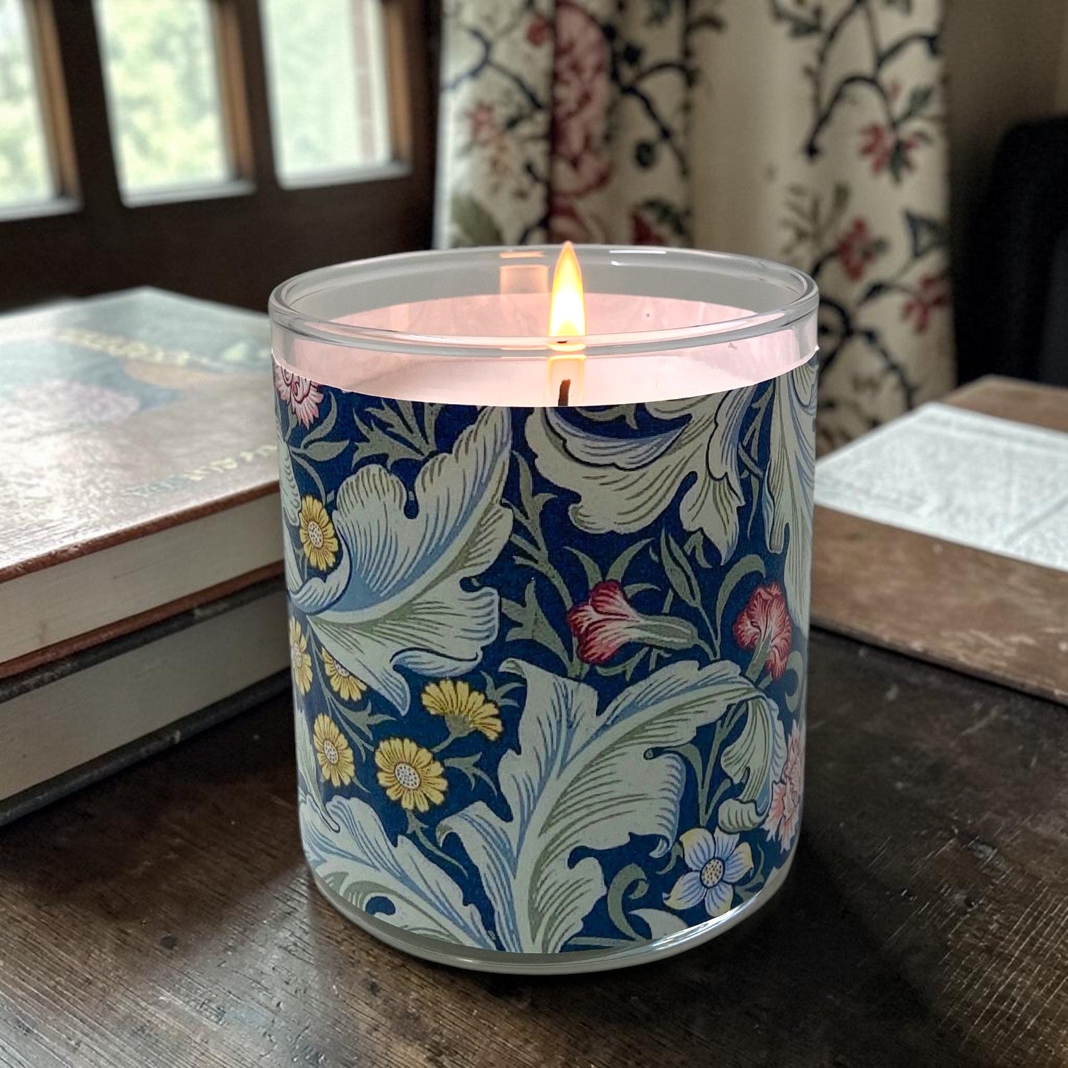 Candle in a decorative tin with floral pattern on a wooden surface