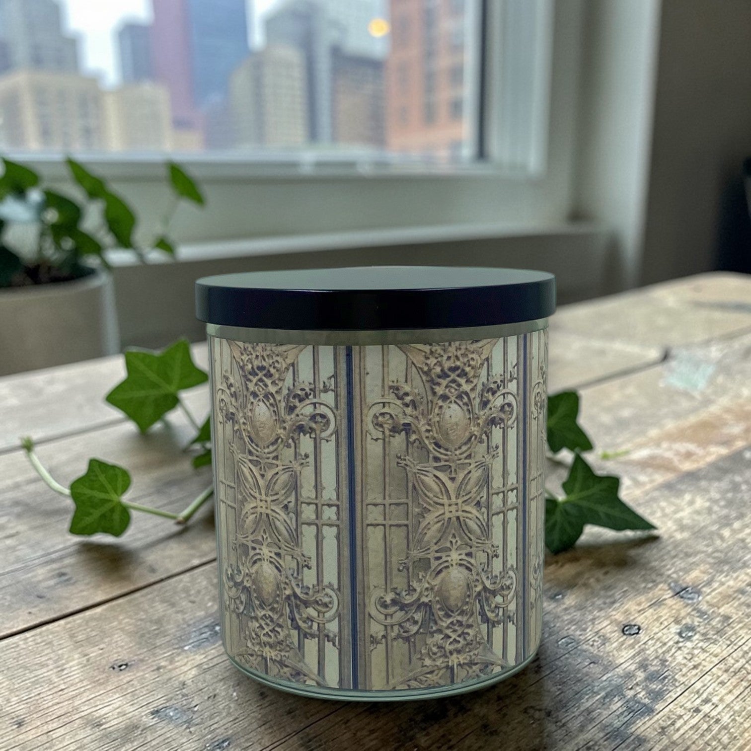 Decorative candle with intricate patterns on a wooden surface with a cityscape in the background