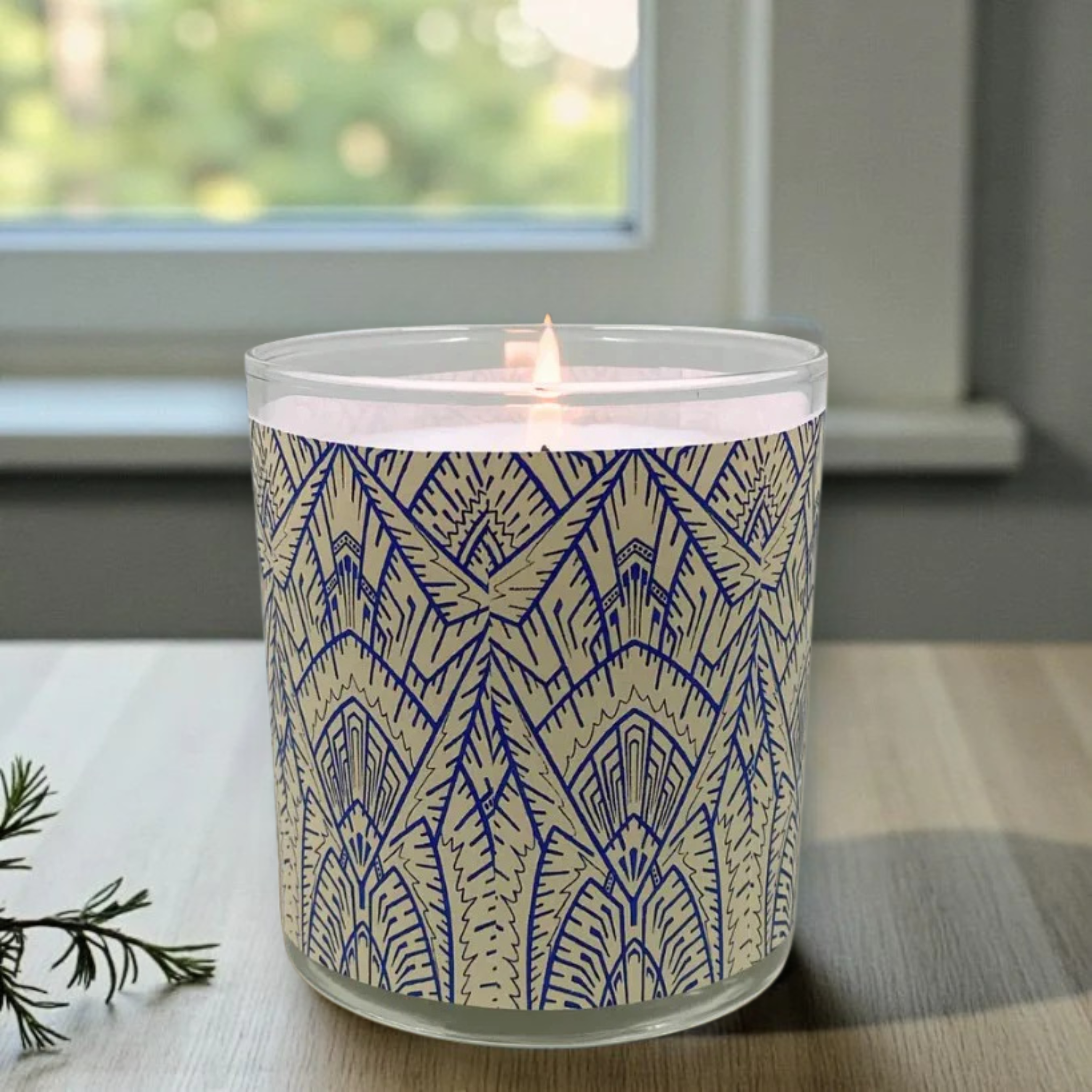 Candle in a glass jar with a blue geometric pattern on a wooden surface.