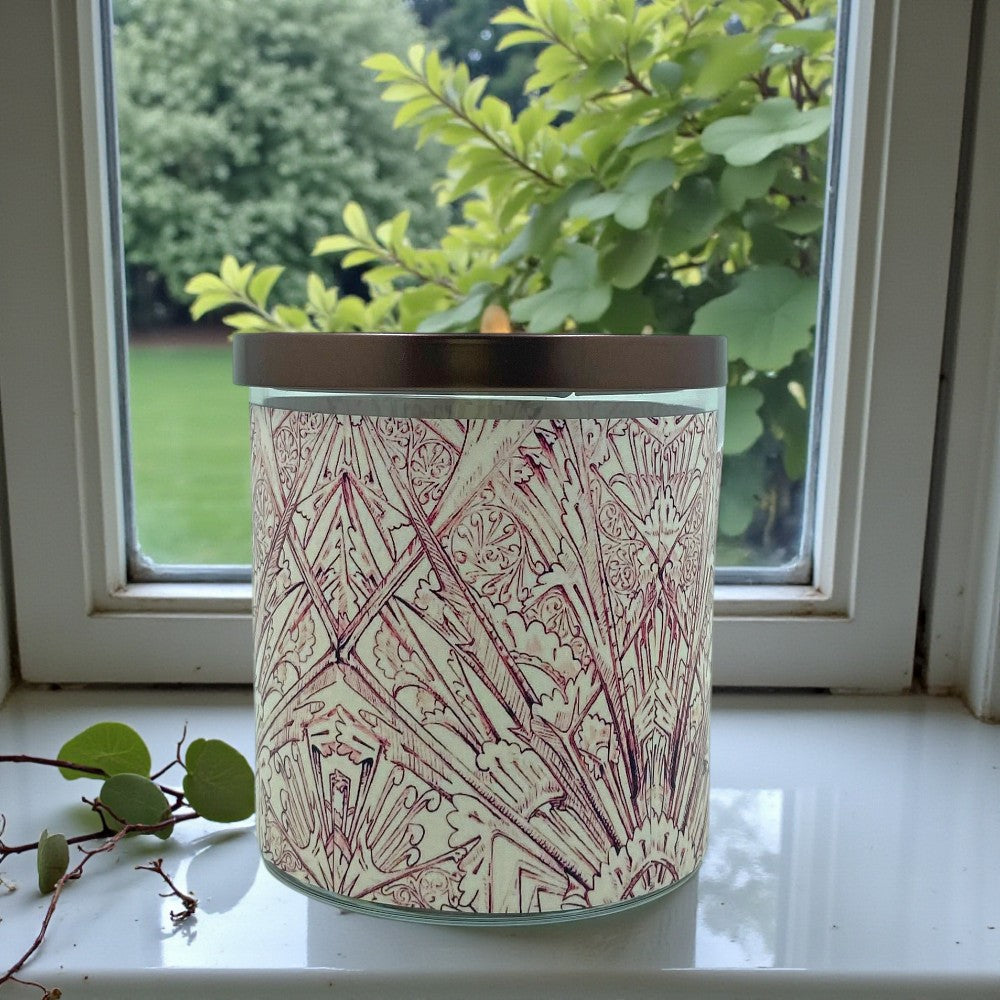 Decorative candle with geometric pattern on a windowsill with greenery outside