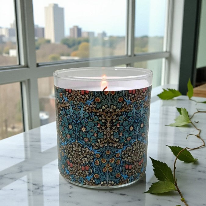 Decorative candle with a patterned label on a marble surface with a cityscape view.