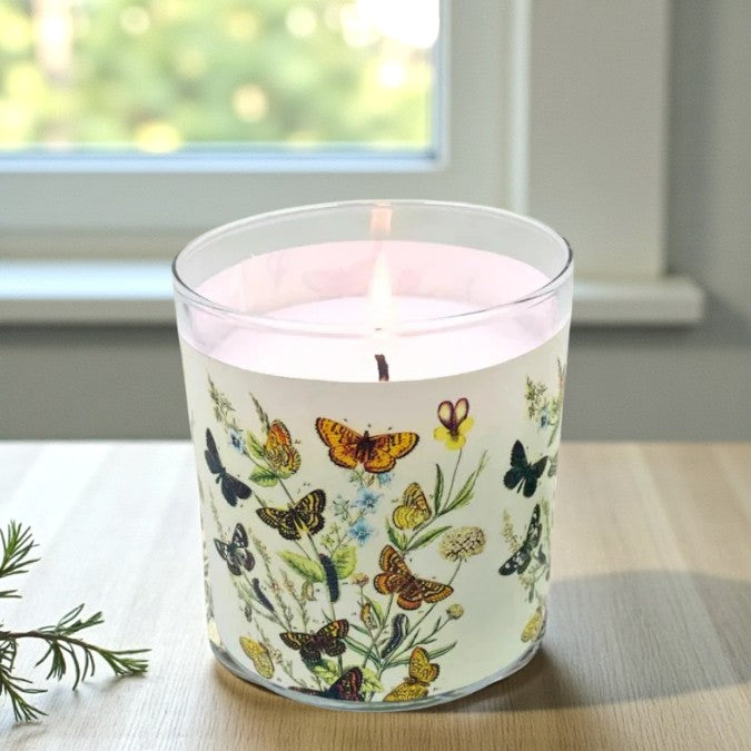Candle with butterfly design on a windowsill