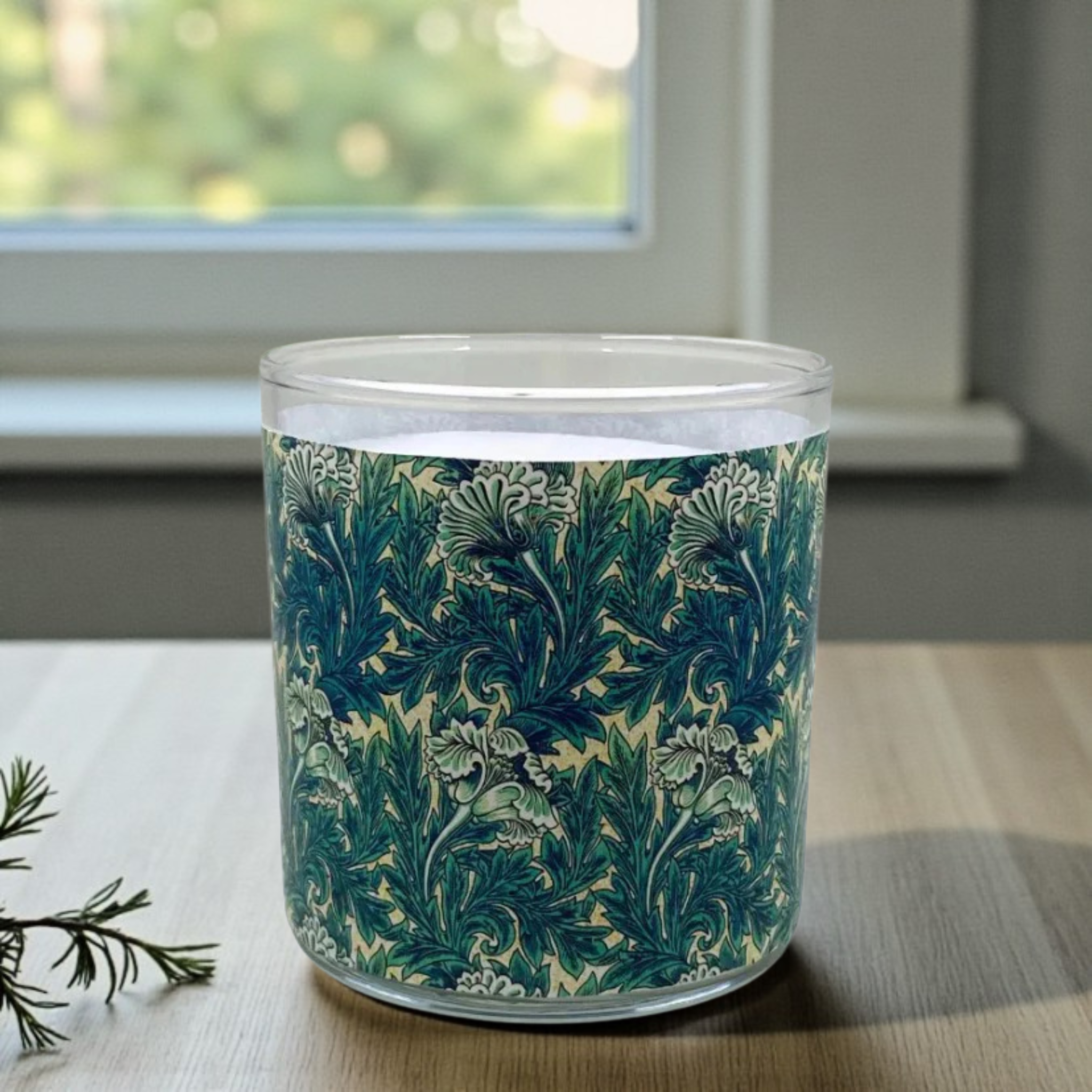 Glass candle with floral pattern on a wooden surface
