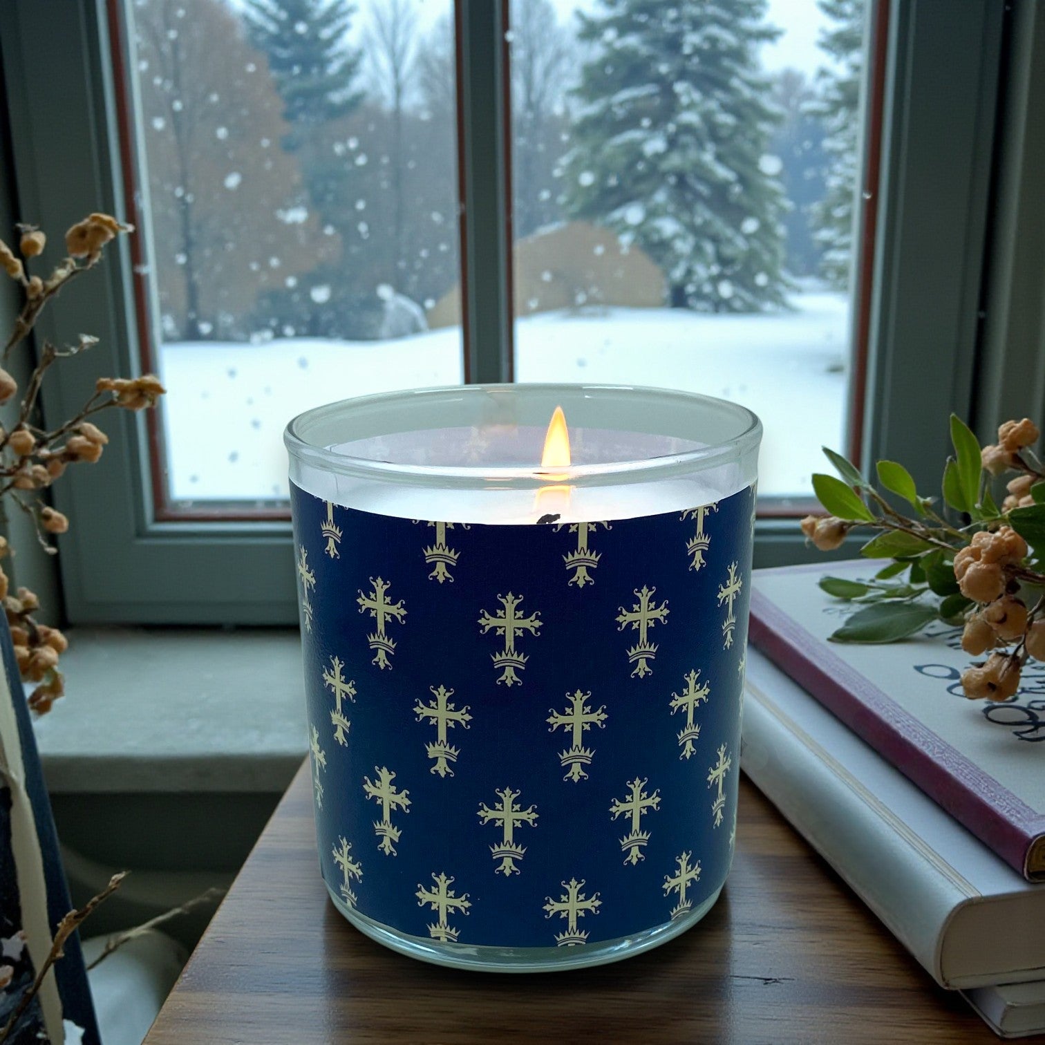 Candle with a blue patterned label in front of a snowy window