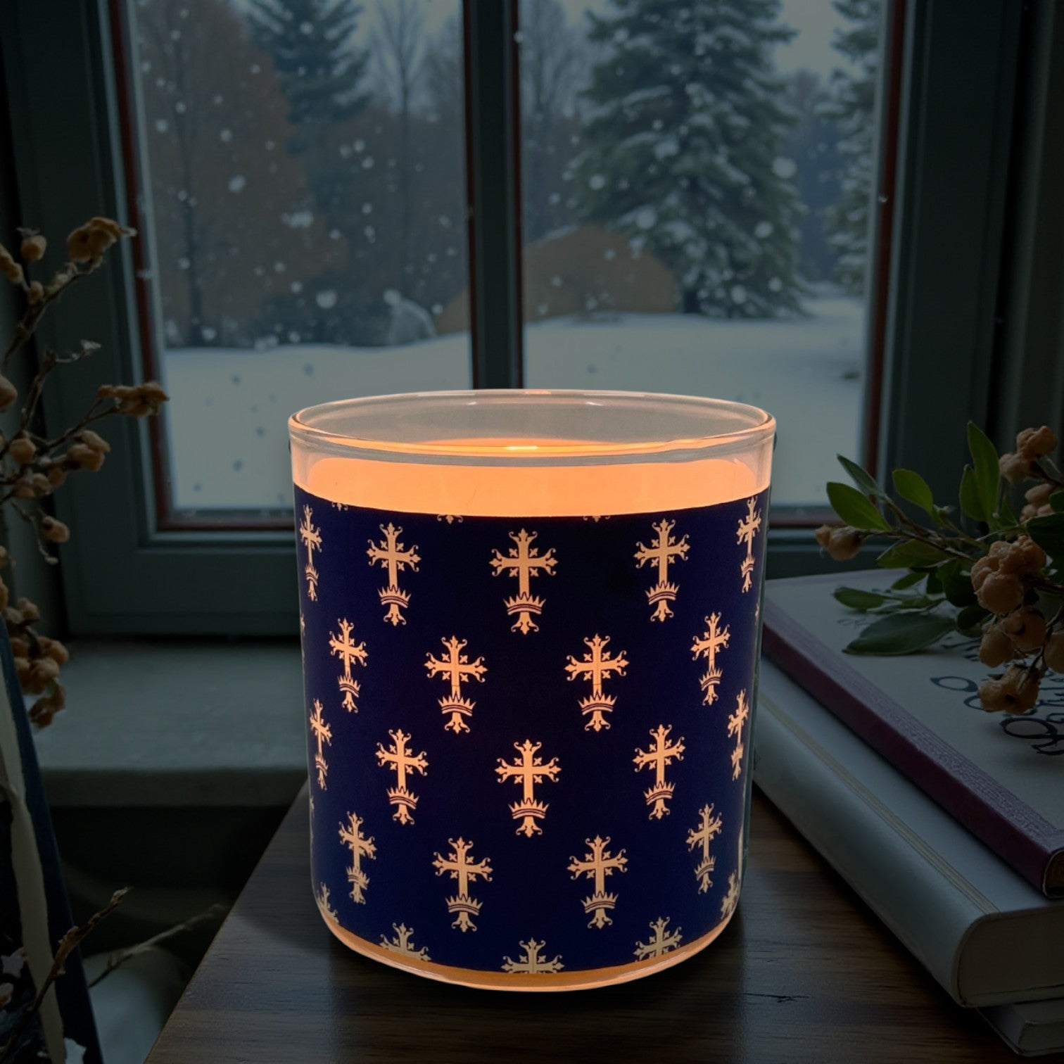 Decorative candle with gold crosses on a blue background, glowing softly.