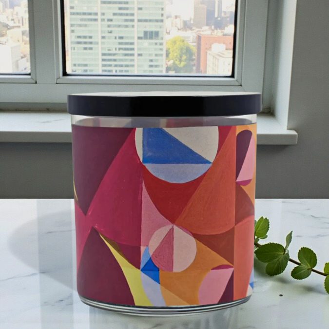 Colorful geometric-patterned cylindrical container on a marble surface with a window view in the background