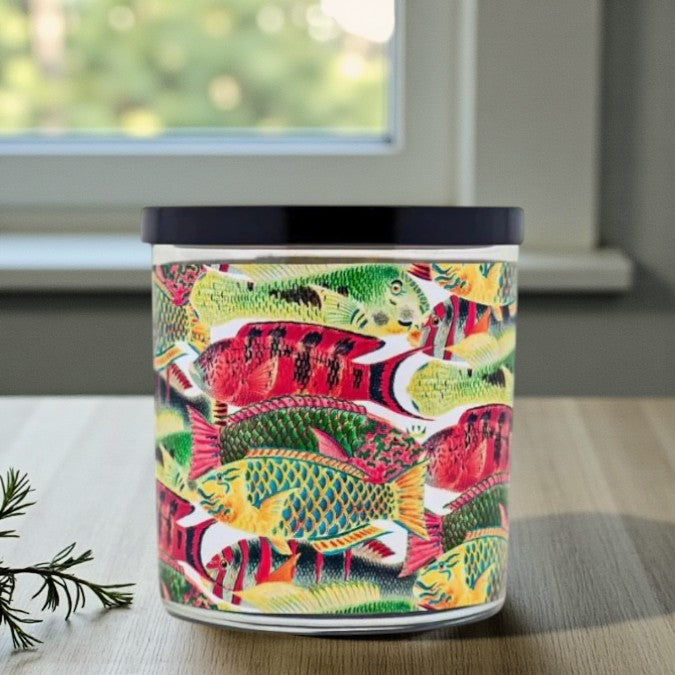 Colorful fish-patterned candle on a surface with a window in the background