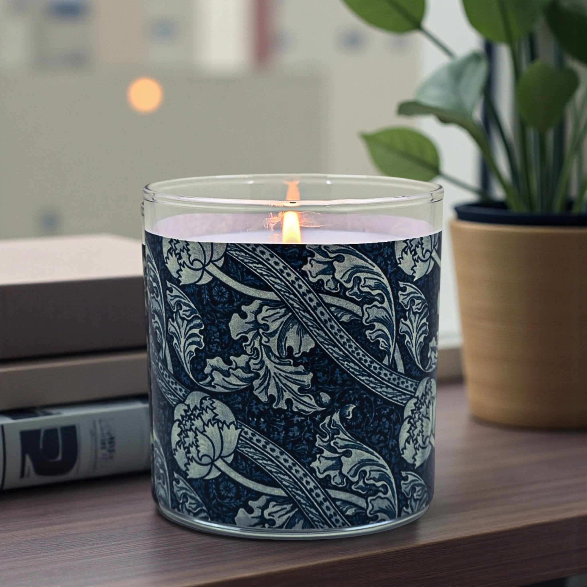 Candle with decorative navy label on a wooden surface with a plant and books in the background