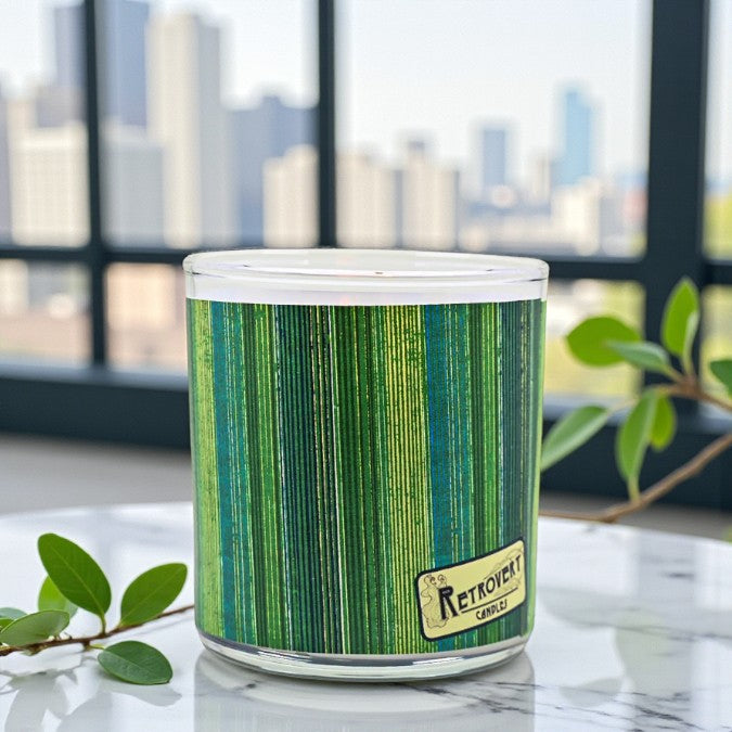Candle with green and blue striped pattern on a marble surface with a cityscape in the background