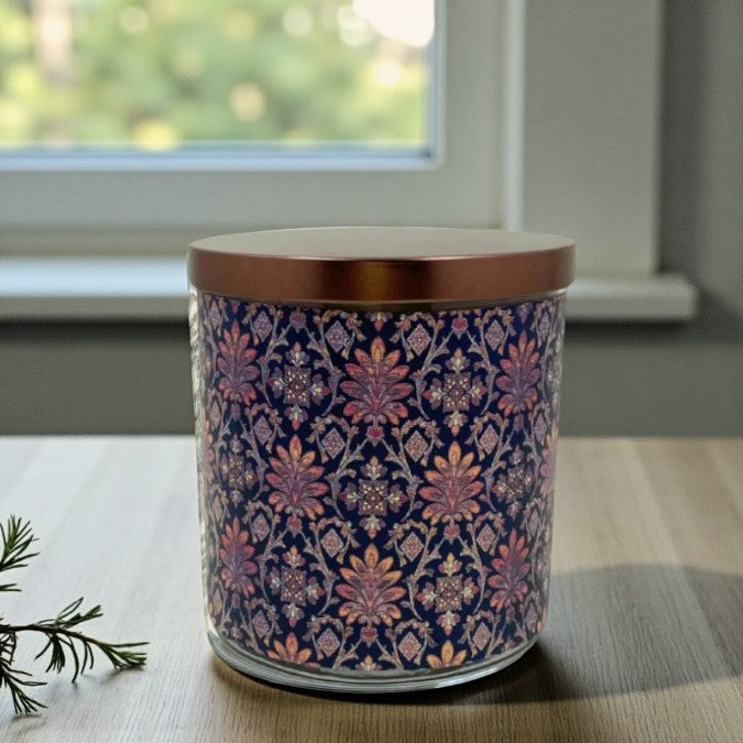 Decorative candle with floral pattern on a table near a window
